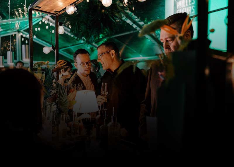 Feiernde Menschen mit Coktails in einer stylischen Szene-Bar